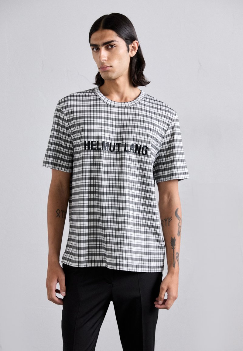 T-shirt à manches courtes noir et blanc à carreaux avec un col rond et "HELMUT LANG" imprimé sur la poitrine. Confectionné en coton.