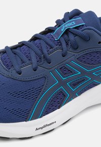 Shoe sportiv de culoare albastru închis, cu partea superioară din plasă, accente turcoaz și o talpă albă cu sigla "AmpliFoam+".