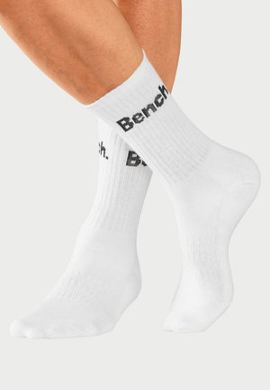 White cotton socks with ribbed design, featuring black text "Bench." printed on the cuff. Smooth texture and standard crew length.