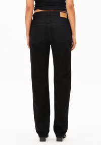 Jeans en denim noir avec une coupe droite, dotés d'une étiquette en cuir à l'arrière, de deux poches arrière et d'une finition lisse.