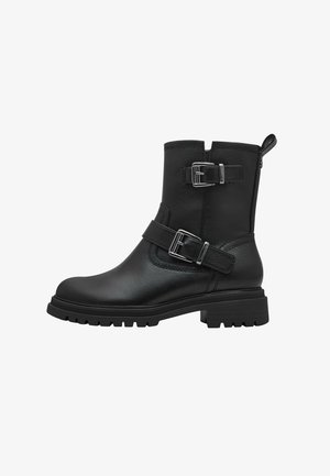Bottines en cuir noir avec une texture lisse, ornées de deux accents de boucles en argent et dotées d'une semelle en caoutchouc robuste pour une meilleure traction.