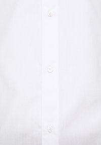 Camisa blanca de botones con una textura suave, seis botones equidistantes y un diseño de cuello clásico. Apta para vestir formal.