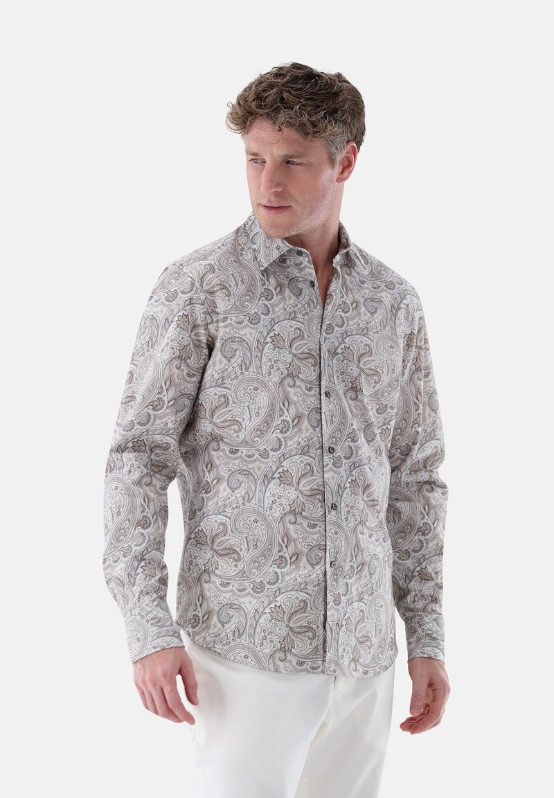 Long-sleeve button-up shirt in a beige and brown paisley pattern, featuring a spread collar and dark buttons, worn with white pants.