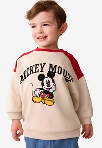 Beige sweatshirt met rode raglanmouwen, "MICKEY MOUSE" tekst en een afbeelding van Mickey Mouse. Zachte stof met ribgebreide manchetten.