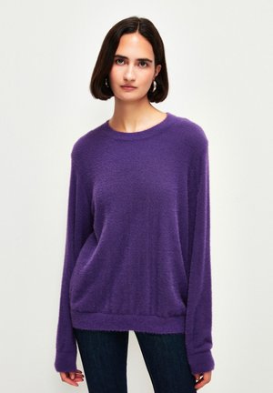 Paarse oversized trui van zacht, fluffy materiaal met een ronde halslijn en lange mouwen, voorzien van een geribbelde zoom en boorden.
