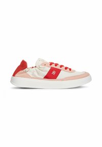 Baskets basses blanches avec détails en suède rouge, lacets rouges et patch logo rouge sur le côté, présentées de profil sur fond blanc.