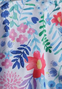 Farverigt blomstermønster på hvidt stof med pink, rød, blå og grønne nuancer samt varierende blomsterformer og bladdesigns.