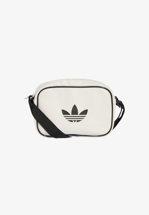 Balta sintētiska crossbody soma ar melno Adidas trefoilu. Somai ir rāvējslēdzēja aizdare, regulējams melns siksniņš un melna apdare.