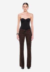 Czarny bezramkowy body z wbudowanymi miseczkami, połączone z brązowymi zamszowymi spodniami dzwonami z lace-up z przodu i metalowymi akcentami.