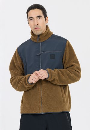 Fleece jacket with brown textured fabric and navy panels; features high collar, zip pocket, and front zip closure. Soft, warm design.