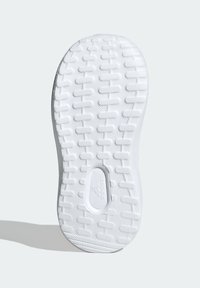Semelle de chaussure de sport blanche avec une surface en caoutchouc texturée présentant un motif géométrique et un logo en relief.