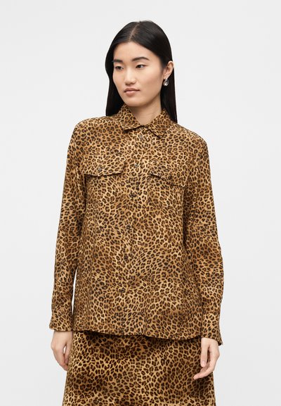Πουκάμισο με κουμπιά σε μοτίβο λεοπάρ σε καφέ και μαύρο χρώμα· διαθέτει δύο τσέπες στο στήθος και γιακά. Μαλακή υφή, εφαρμοστή γραμμή και μακριά μανίκια.