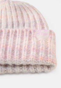Knitted beanie in pastel shades of pink, cream, and lavender. Features ribbed texture and a small lavender logo label at the cuff.