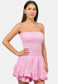 Strapless roze jurk van textiel met textuur, met een gesmokt lijfje en een rucheszoom. Het ontwerp benadrukt een getailleerde silhouet.