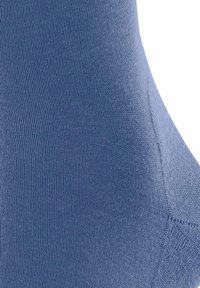 Chaussette en textile bleu avec une texture lisse, présentant un design côtelé et des coutures précises le long des côtés pour un ajustement confortable.