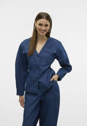 Veste en denim à manches longues, col en V et deux poches poitrine, dotée de gros boutons et d'une coupe décontractée, en tissu bleu foncé.