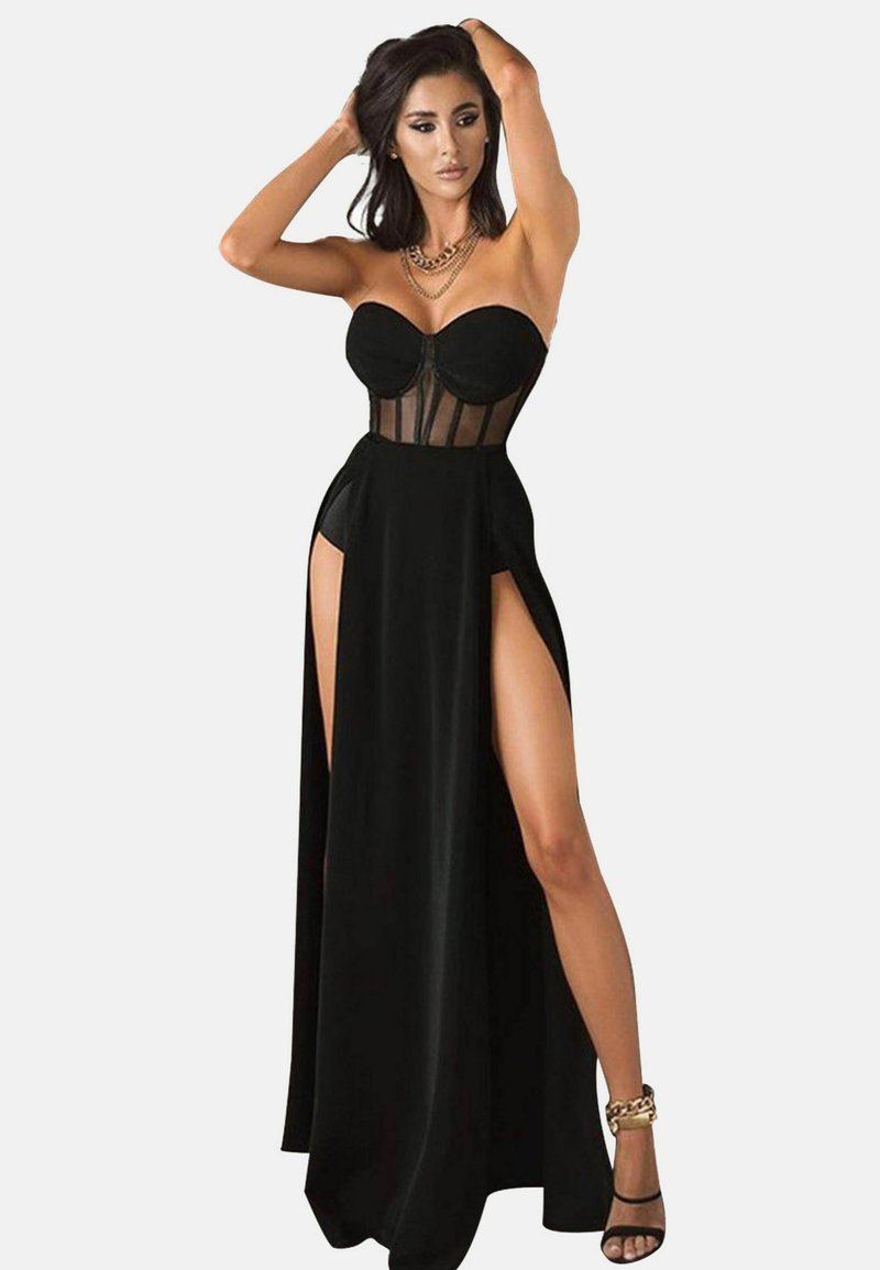 Schwarzes Abendkleid mit schulterfreiem Design, transparentem Mesh-Oberteil, hohen Schlitzen und einem fließenden Rock. Akzentuiert mit einer goldenen Kette.