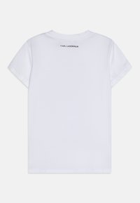 Vit bomull t-shirt med rundad halsringning och korta ärmar. Har en tryckt logotyp "KARL LAGERFELD" centrerad på övre ryggen. Slät textur.