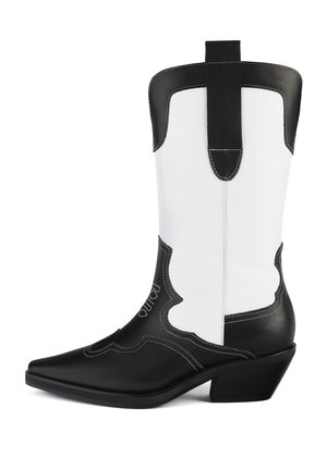 Czarno-biała kowbojska bootka wykonana z syntetycznej skóry, z ostrym noskiem, falistym wzorem i niskim obcasem blokowym. Zauważalny detal w postaci przeszyć.