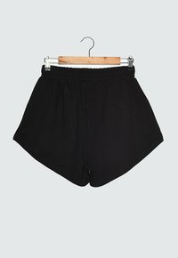 Schwarze Sportshorts mit einem elastischen Bund, hergestellt aus einem weichen, dehnbaren Material. Sie haben eine lockere Passform und weite Beinöffnungen.