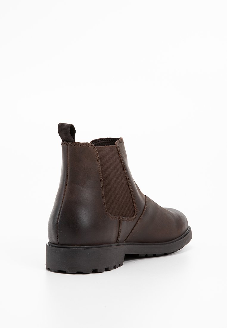 Bottines en cuir marron avec panneaux latéraux élastiques, bout rond et semelle en caoutchouc texturé. Tirant à l'arrière pour un enfilage facile.