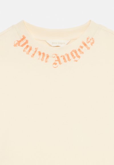 Μπεζ τοπ με στρογγυλή λαιμόκοψη και τυπωμένο το «Palm Angels» σε ξεθωριασμένη πορτοκαλί παλιά αγγλική γραμματοσειρά γύρω από το γιακά.