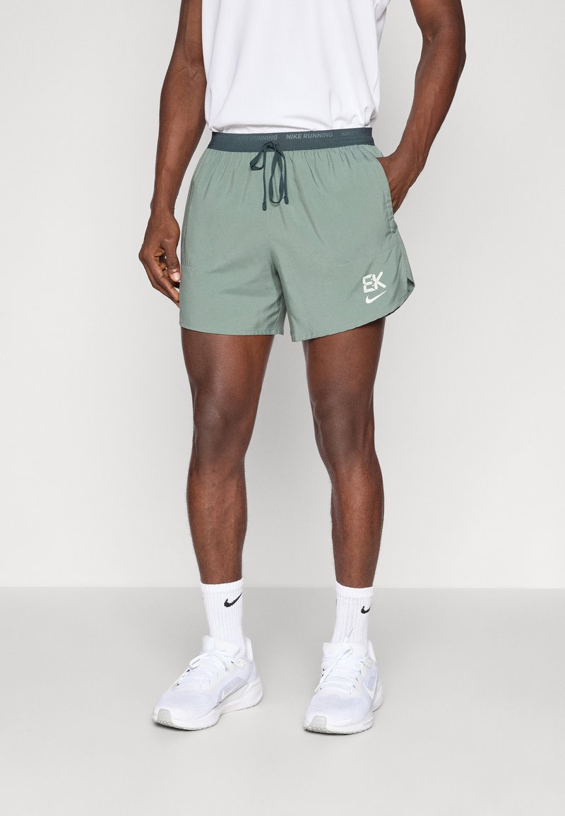 Shorts deportivos verdes hechos de una tela ligera, con cintura ajustable, bolsillos laterales y un acento de logo en el dobladillo.
