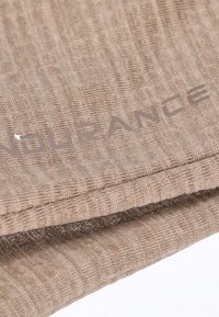 Tessuto marrone chiaro con una trama strutturata, caratterizzato da un logo in rilievo "ENDURANCE" lungo il bordo. Le pieghe mostrano una caduta morbida.
