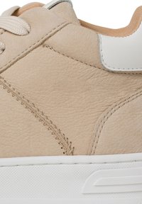 Sneaker in pelle beige con una parte superiore testurizzata, accenti bianchi minimali e suola in gomma con un sottile dettaglio in rilievo.