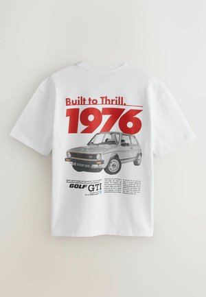 Valge puuvillane T-särk, mille seljal on punane ja must graafiline print, kus on kujutatud tekst "Built to Thrill. 1976" ja Golf GTI illustreerimine.