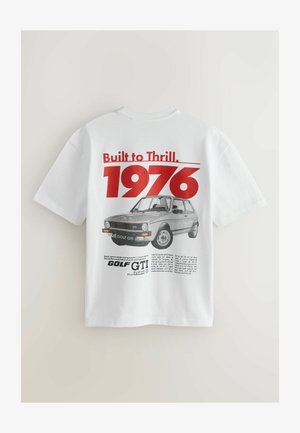Balts kokvilnas T-krekls ar sarkanu un melnu grafisku dizainu uz muguras, kurā attēlots teksts "Built to Thrill. 1976" un Golf GTI ilustrācija.