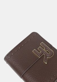 Portafoglio in pelle marrone con superficie testurizzata, caratterizzato da un logo color oro e cuciture dettagliate lungo i bordi. Forma compatta e rettangolare.