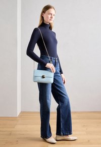 Námořnický rolák, džíny s vysokým pasem modré barvy, béžové baleríny a světle modrá crossbody taška se zaobleným zlatým zapínáním. Hladké textury a strukturované tvary.