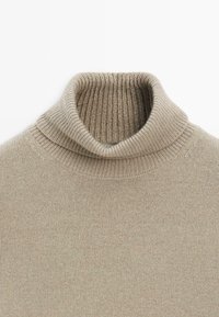 Maglione beige a collo alto con colletto a costine e trama a maglia fine. Tessuto morbido senza motivi o decorazioni visibili.