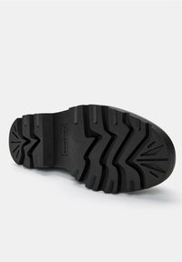 Talpa de pantof negru din cauciuc, cu șanțuri adânci și unghiulare și dâre, având un logo imprimat vizibil pe lateral. Textură netedă în ansamblu.