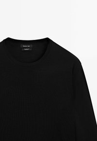 Černý svetr s kulatým výstřihem vyrobený ze 100% merino vlny. Hladká textura, dlouhé rukávy a nenápadný design s etiketou na výstřihu.
