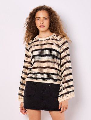 Strickpullover mit einem beigen und schwarzen Streifenmuster, Rundhalsausschnitt und langen Ärmeln, kombiniert mit einem schwarzen Jeansrock.
