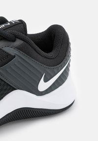 Sort sportssko i mesh og syntetiske materialer, med polstret krave, hvid Nike swoosh og struktureret gummiydersål for godt greb.