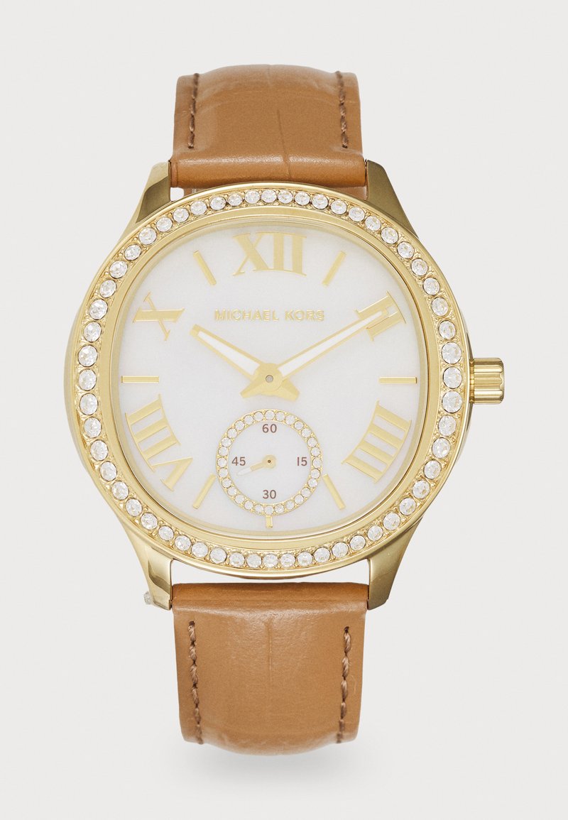 Montre dorée avec un cadran crème, des chiffres romains et des accents en cristal. Dispose d'un bracelet en cuir marron et d'un sous-cadran pour les secondes.