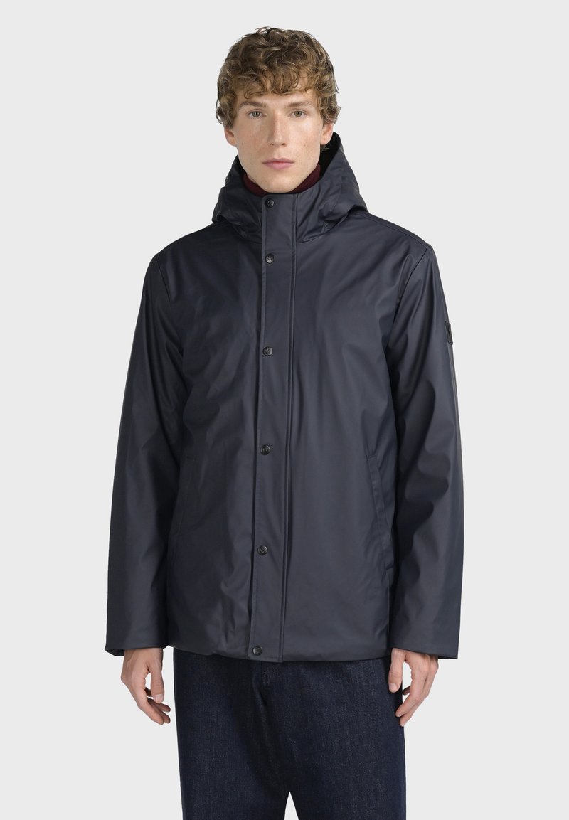 Námořnická modrá voděodolná bunda s vysokým límcem, zapínáním na patentky a dlouhými rukávy. Vyrobeno z hladkého, lehkého materiálu.