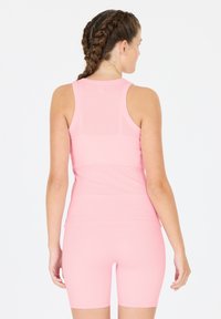 Helles rosa, geripptes Sport-Tanktop mit abgerundetem Ausschnitt und Racerback-Design, kombiniert mit passenden, figurbetonten Shorts, die beide eine glatte Textur zeigen.