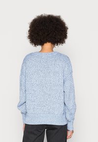 Light blue knitted sweater with a textured pattern, wide neckline, and ribbed cuffs and hem. Loose fit, long sleeves, casual design.