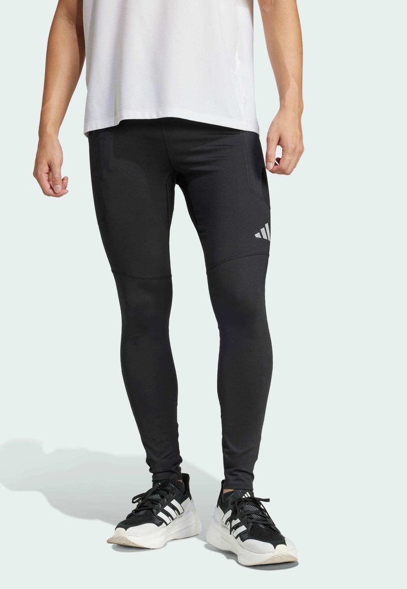 Leggings atléticos negros hechos de un material elástico con un diseño ajustado, que presentan costuras horizontales y un acento de logo en el muslo.