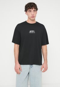 Μαύρο βαμβακερό μπλουζάκι με λευκό γραφικό "MICKEY CALIFORNIA FOOTBALL TEAM" στο στήθος. Ίσια εφαρμογή και κοντά μανίκια.