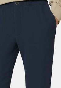 Pantaloni blu navy con una texture liscia, cintura elasticizzata e una tasca frontale. I punti di cucitura sono discreti e il design è progettato per il comfort.