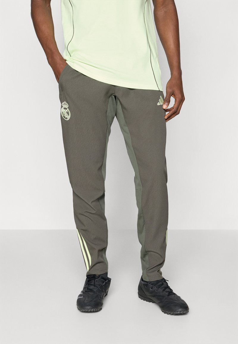Olive green athletic pants with stretchy material, featuring light green stripes on the sides and a logo on the left thigh. Designed for comfort.