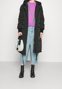 Svart vadderad jacka, lila sweatshirt, ljusblå denimkjol med slits, svarta ankelstövlar och en liten grå handväska med svarta detaljer.