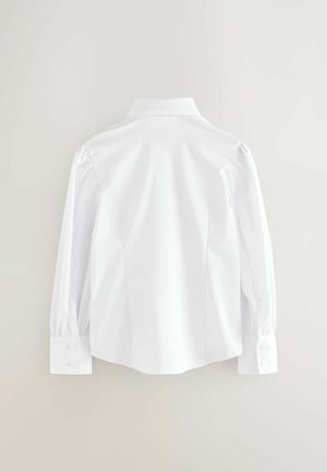 Chemise blanche à manches longues avec un col pointu, des épaules structurées et des poignets boutonnés. Fabriquée en tissu lisse et léger.