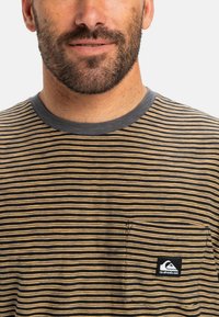 Gestreept t-shirt met korte mouwen in geel en zwart, met een ronde grijze kraag en een borstzak met een logo-label. Zachte stofstructuur.