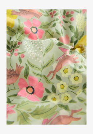 Tissu présentant un fond vert avec des motifs floraux et animaliers multicolores. Les détails incluent des fleurs roses, des fleurs jaunes et des oiseaux bruns.